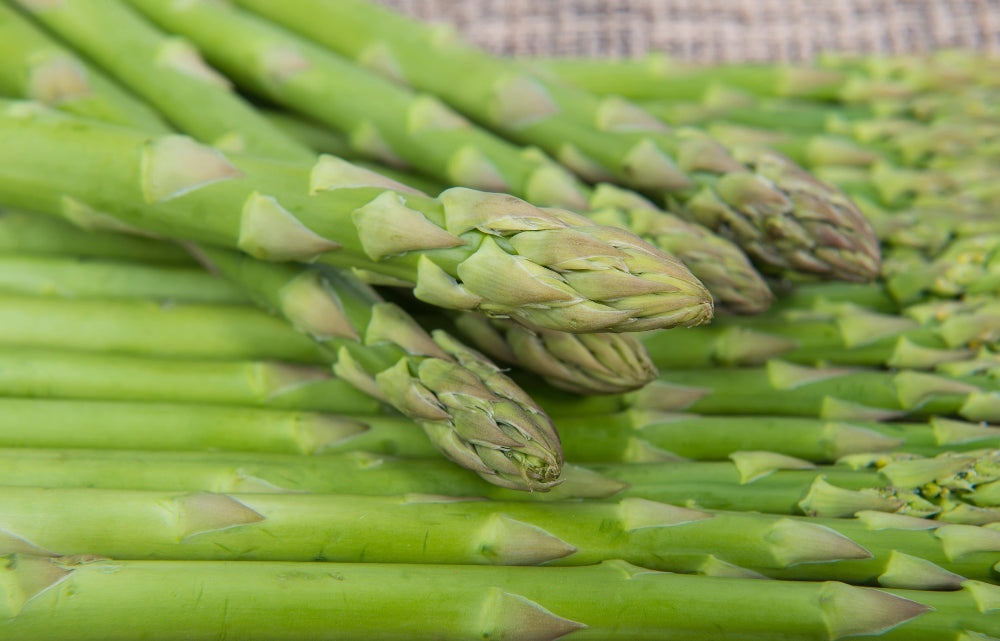 A close-up of vibrant, fresh asparagus spears, ready for cooking and grown with Soil Smiles organic fertilizer for optimal flavor.